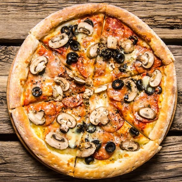 Wild Pepper Pizza with mushrooms, black olives, and pepperoni, sliced on a rustic wooden table.