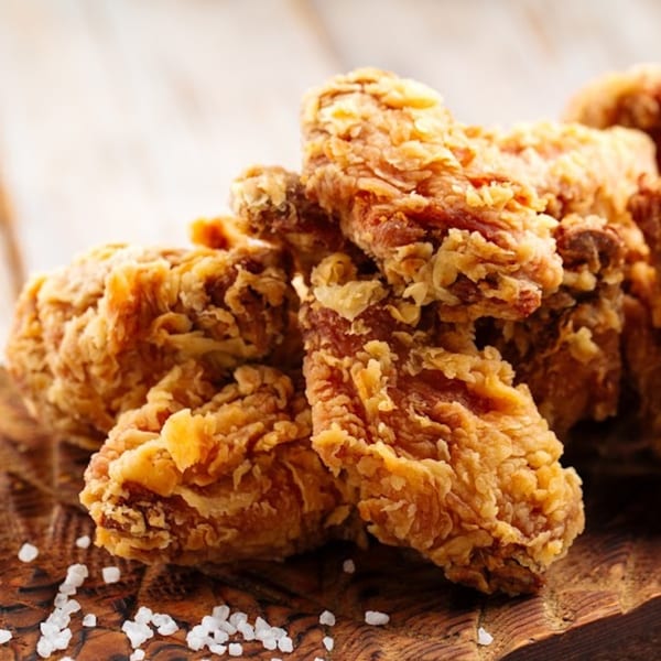 Crispy fried chicken wings with coarse salt on a rustic wooden board.