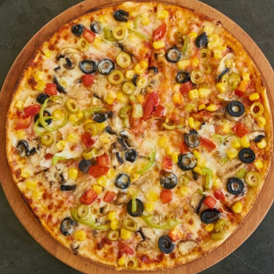 Wild Pepper Pizza's vibrant vegetarian pizza with olives, corn, peppers, and mushrooms on a wooden board.