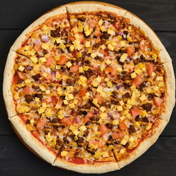 Wild Pepper Pizza's taco pizza, topped with ground beef, diced tomatoes, red onions, and cheese cubes.