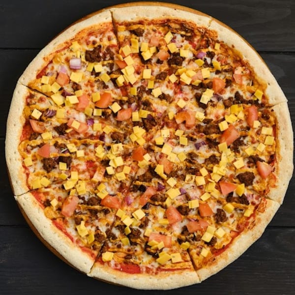 Wild Pepper Pizza's taco pizza, topped with ground beef, diced tomatoes, red onions, and cheese cubes.